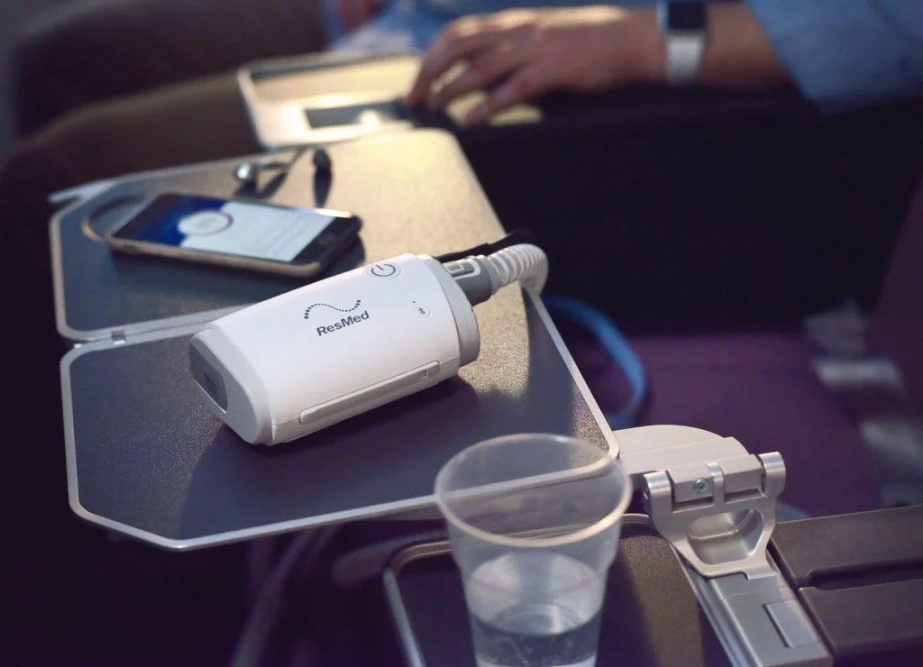 CPAP portátil AirMini ResMed sobre bandeja durante deslocamento de viagem