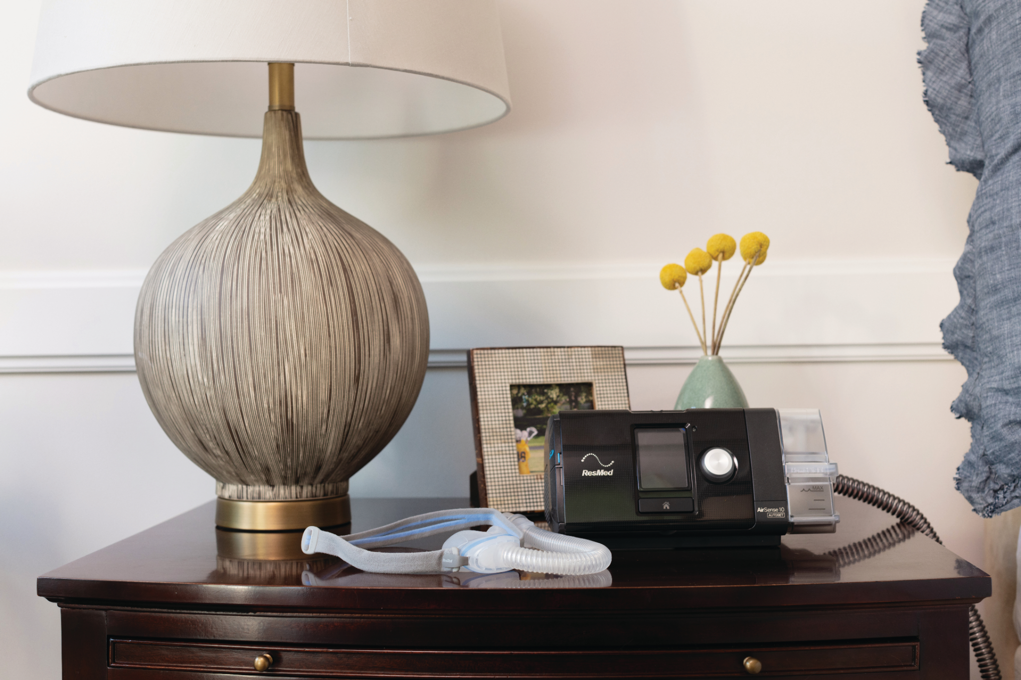 CPAP ResMed AirSense 10 AutoSet sobre mesa de cabeceira com máscara e tubo
